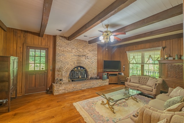 living room with beam ceiling, light wood-type flooring, plenty of natural light, and wood walls