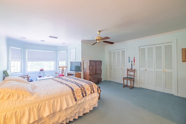 bedroom featuring ornamental molding, ceiling fan, carpet floors, and two closets