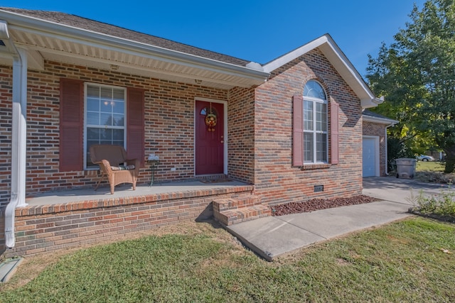 property entrance featuring a yard, a garage, and covered porch