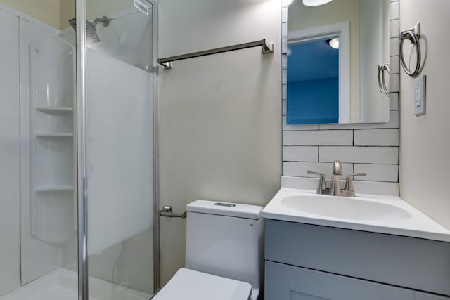 bathroom with vanity, backsplash, toilet, and a shower with door