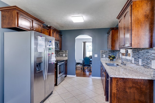 kitchen with decorative backsplash, light tile patterned flooring, sink, and stainless steel appliances