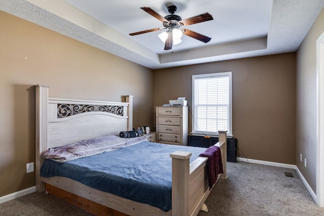 carpeted bedroom featuring a raised ceiling and ceiling fan