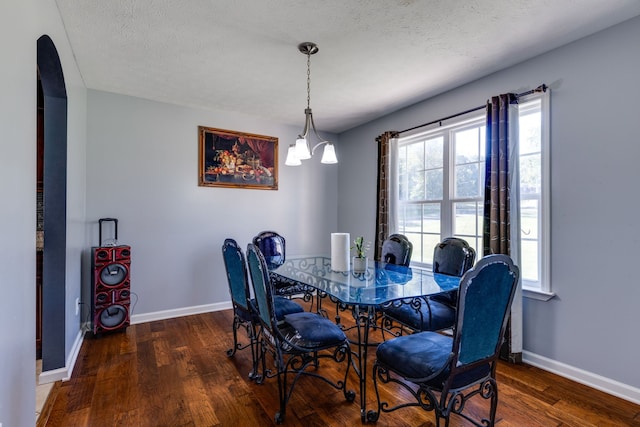 dining area featuring an inviting chandelier, a textured ceiling, and dark hardwood / wood-style flooring