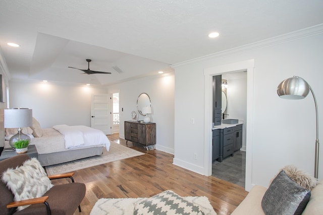 bedroom with light hardwood / wood-style floors, ornamental molding, ensuite bath, and ceiling fan