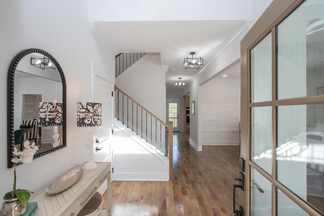 foyer featuring a notable chandelier, dark hardwood / wood-style floors, and ornamental molding