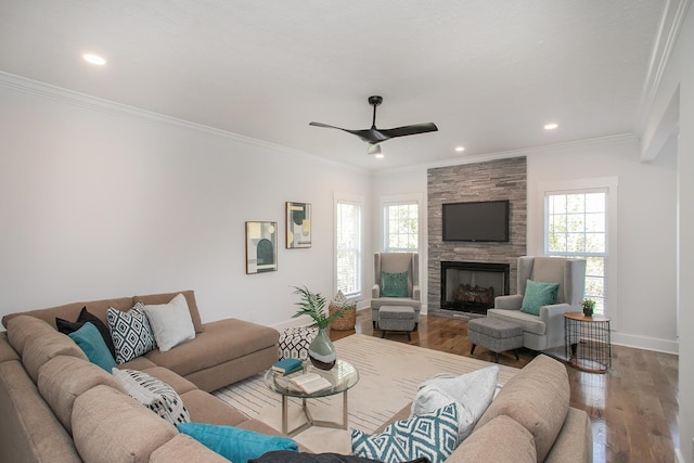 living room with a stone fireplace, light hardwood / wood-style floors, a healthy amount of sunlight, and crown molding