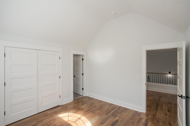 unfurnished bedroom with vaulted ceiling, a closet, and dark wood-type flooring