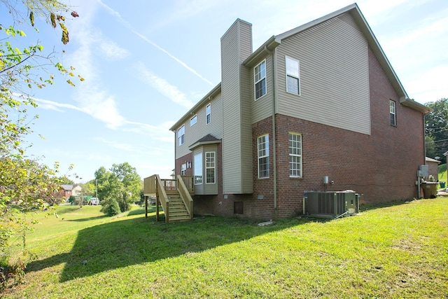 back of house featuring central AC unit and a lawn