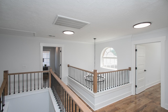 hall featuring ornamental molding, a textured ceiling, a notable chandelier, and dark wood-type flooring