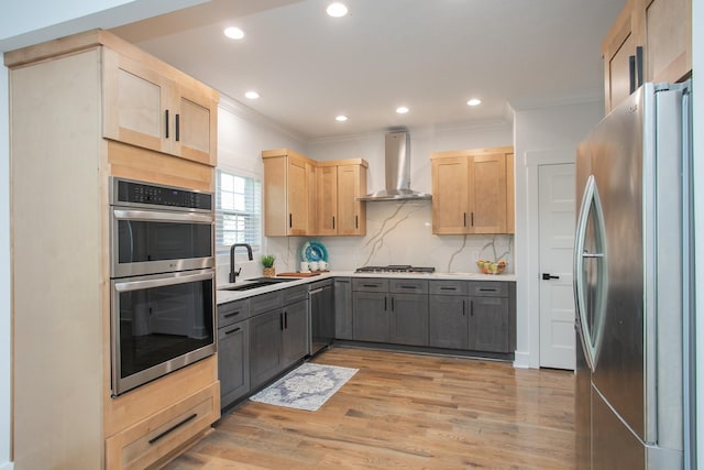 kitchen with gray cabinetry, light brown cabinets, wall chimney range hood, and stainless steel appliances