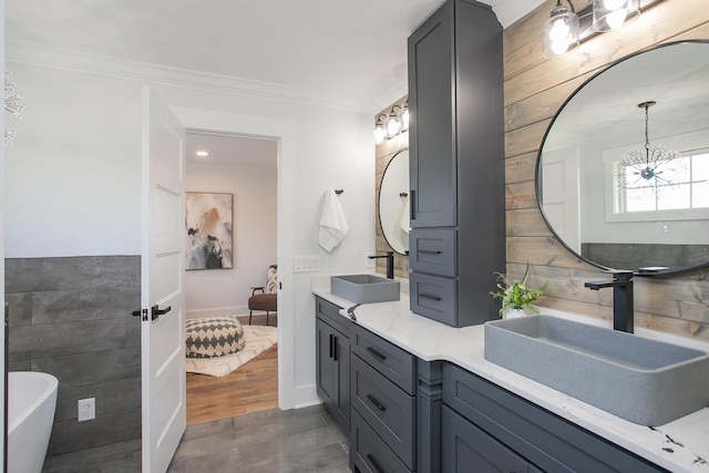 bathroom with a chandelier, a tub, hardwood / wood-style floors, ornamental molding, and vanity