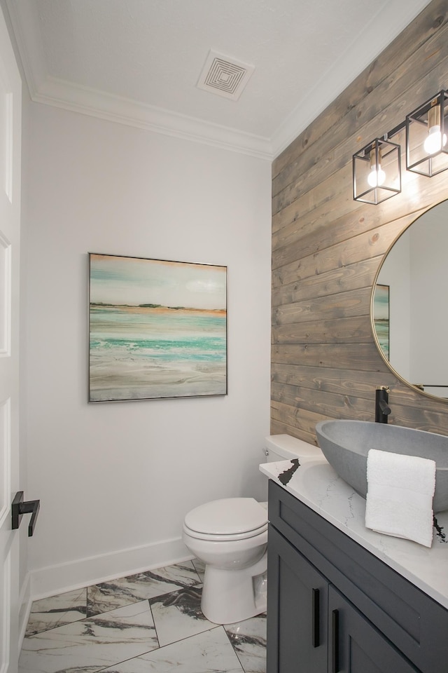 bathroom featuring crown molding, wood walls, vanity, and toilet