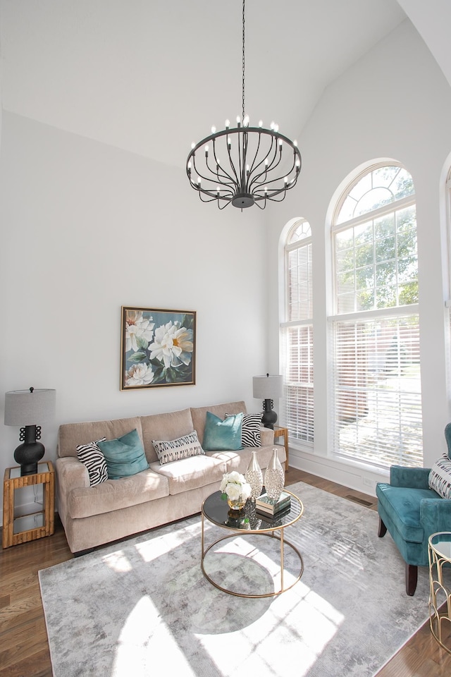 living room with vaulted ceiling, a notable chandelier, and dark wood-type flooring