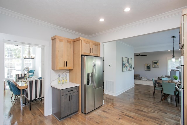 kitchen featuring hanging light fixtures, wood-type flooring, light brown cabinets, and stainless steel appliances