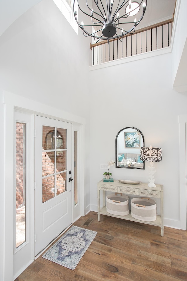 entrance foyer with an inviting chandelier, hardwood / wood-style flooring, and a towering ceiling