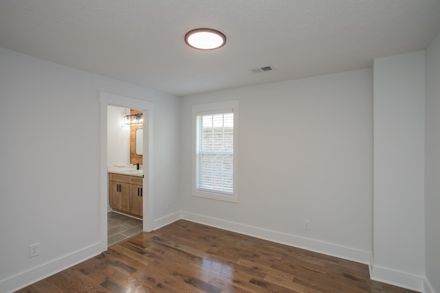 unfurnished room featuring a textured ceiling, sink, and dark wood-type flooring