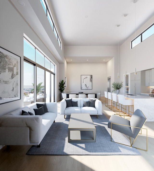 living room with plenty of natural light, wood finished floors, and a towering ceiling