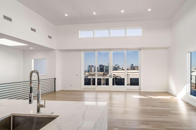 kitchen with visible vents, a city view, light wood-type flooring, and a sink