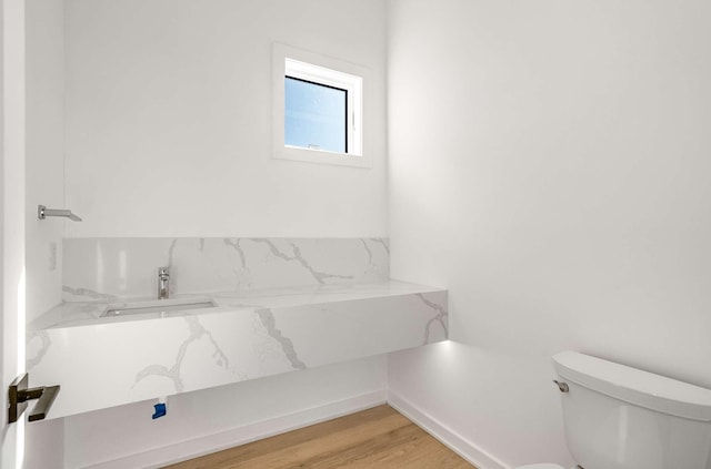 half bath featuring a sink, toilet, and wood finished floors