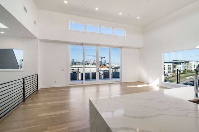 empty room featuring visible vents, a city view, light wood-type flooring, and a high ceiling