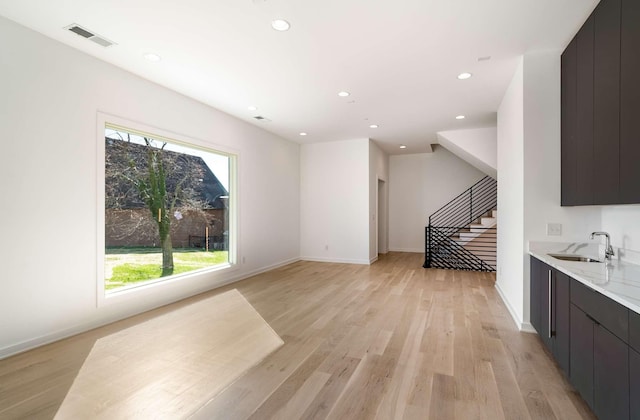 living area featuring recessed lighting, visible vents, light wood-style flooring, and stairway