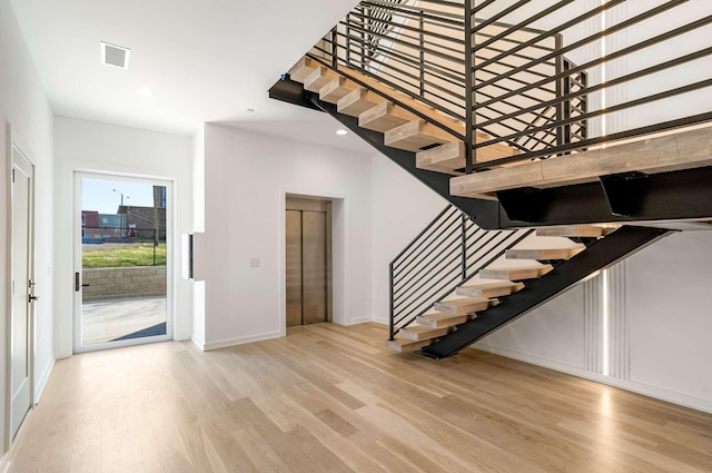 foyer with elevator, visible vents, and wood finished floors