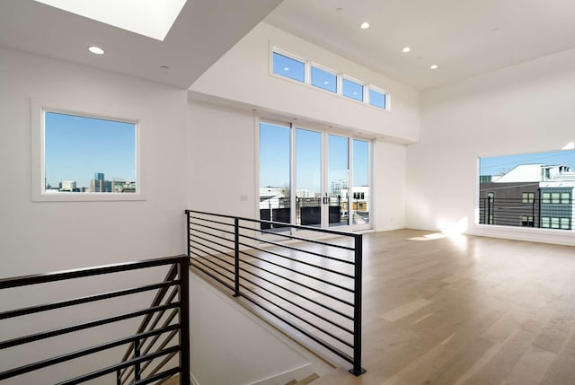 staircase with wood finished floors, a skylight, a high ceiling, recessed lighting, and a view of city