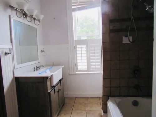 bathroom with tiled shower / bath combo, vanity, plenty of natural light, and tile patterned flooring