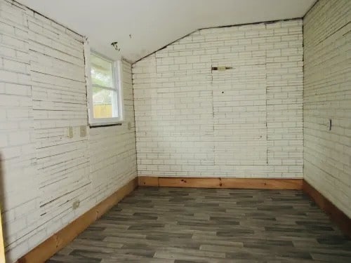 interior space with brick wall and dark hardwood / wood-style floors