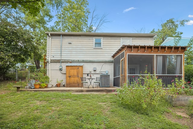 rear view of house featuring a sunroom and a lawn