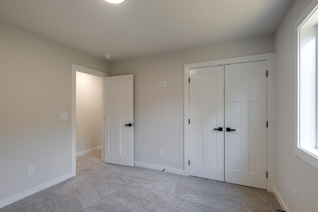 unfurnished bedroom featuring light carpet and a closet