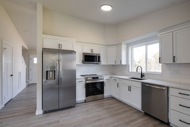 kitchen with sink, white cabinets, stainless steel appliances, and light wood-type flooring