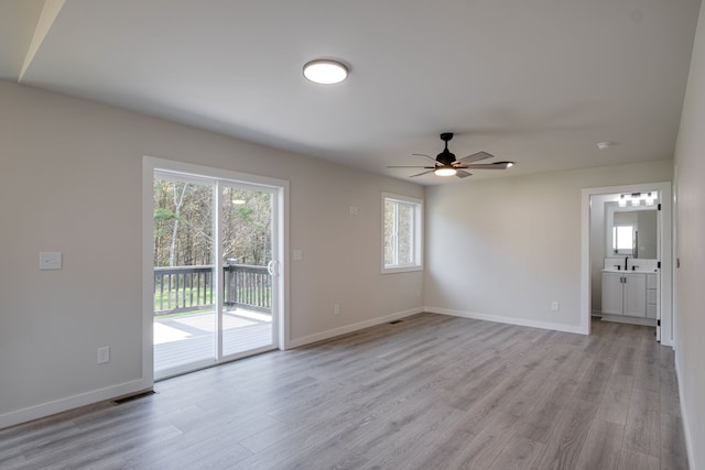 empty room featuring plenty of natural light, ceiling fan, sink, and light hardwood / wood-style flooring