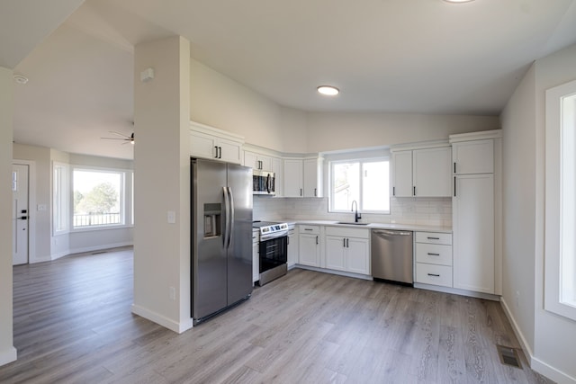 kitchen featuring white cabinetry, a healthy amount of sunlight, light wood-type flooring, and appliances with stainless steel finishes