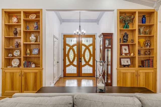 entryway with light hardwood / wood-style floors, a chandelier, ornamental molding, and french doors