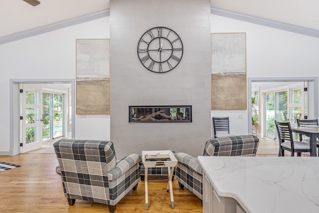 living room with crown molding, light hardwood / wood-style flooring, and lofted ceiling