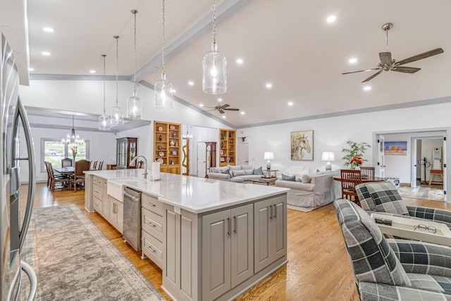 kitchen featuring a center island with sink, pendant lighting, vaulted ceiling with beams, and stainless steel appliances