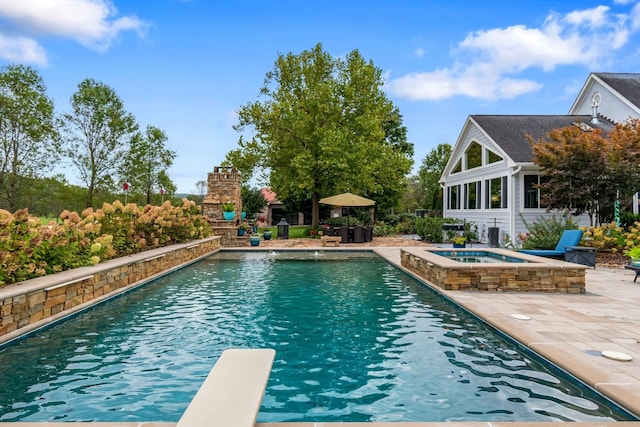 view of swimming pool with an in ground hot tub, a patio area, an outdoor stone fireplace, and a diving board