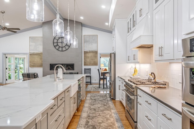 kitchen featuring vaulted ceiling, white cabinetry, appliances with stainless steel finishes, and decorative light fixtures