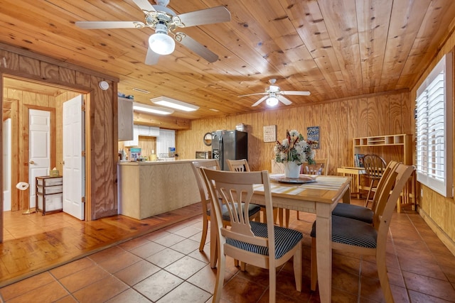 dining space with wood walls, wooden ceiling, and tile patterned flooring