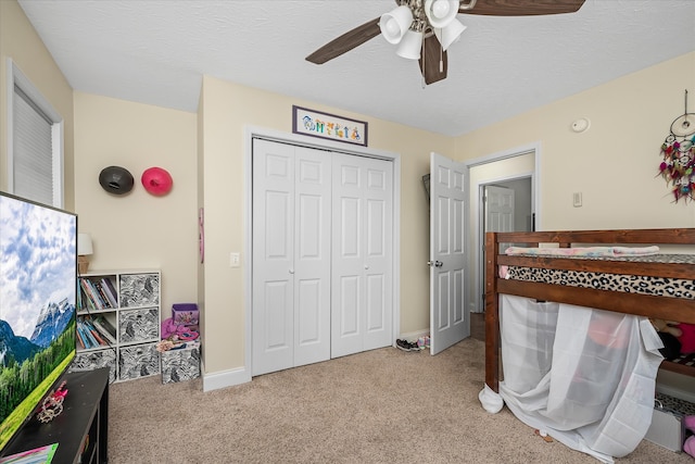 carpeted bedroom with a closet, a textured ceiling, and ceiling fan