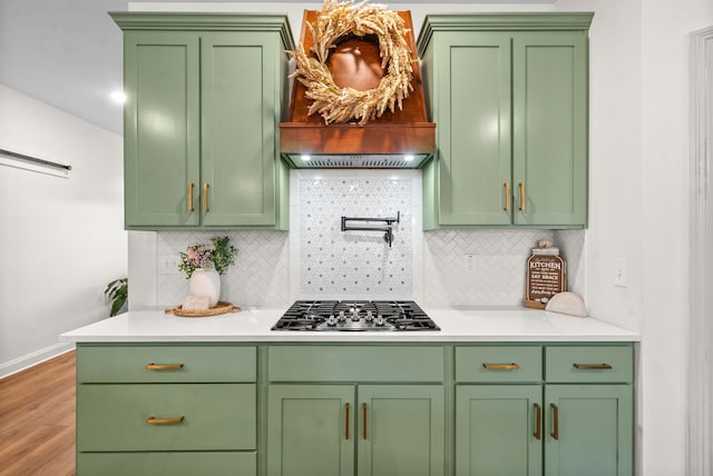 kitchen with stainless steel gas stovetop, premium range hood, hardwood / wood-style floors, and decorative backsplash