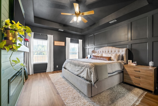 bedroom featuring wood-type flooring, a tray ceiling, and ceiling fan