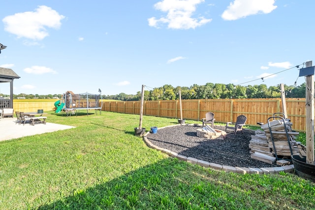 view of yard featuring a fire pit, a trampoline, and a patio area