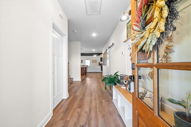 hall featuring a barn door and light wood-type flooring