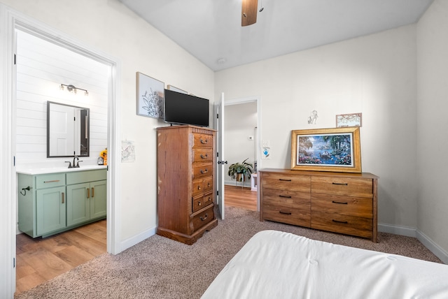 bedroom featuring ceiling fan, light hardwood / wood-style flooring, connected bathroom, and sink