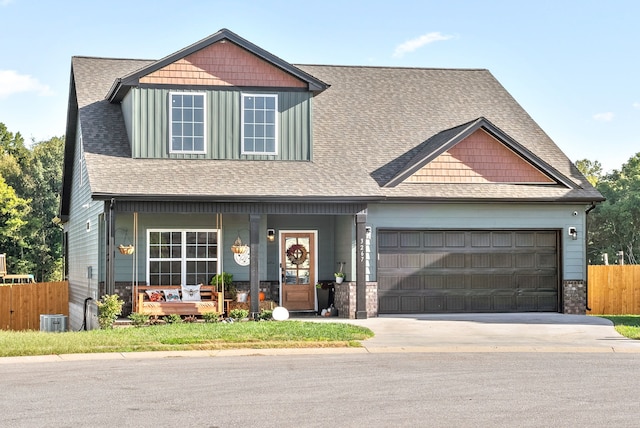 craftsman-style home with a garage, cooling unit, and covered porch