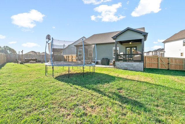 back of property featuring a trampoline and a yard