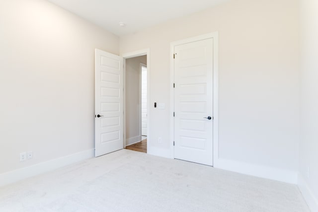 unfurnished bedroom featuring light carpet and a closet