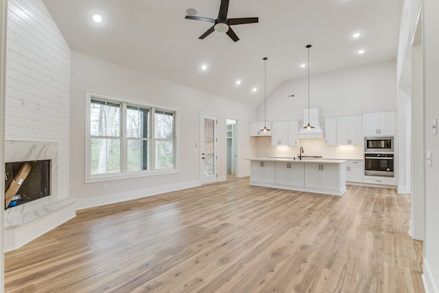 unfurnished living room featuring a fireplace, light hardwood / wood-style flooring, ceiling fan, and sink